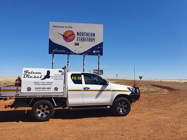 A Falcon Diesel service ute, fitted out for mechanical and auto-electrical work, parked at the Welcome to the Northern Territory border sign