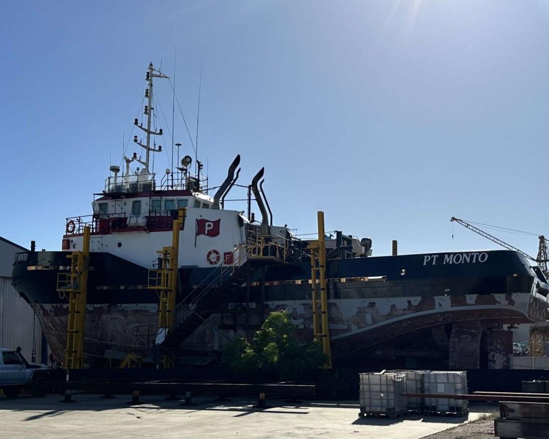 The tug PT Monto up on the hardstand on keel blocks, access staging alongside and the hull stripped back below the waterline