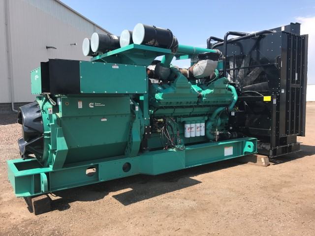 A large Cummins Power Generation diesel generator set standing on gravel beside an industrial shed, radiator at one end and air cleaners on top